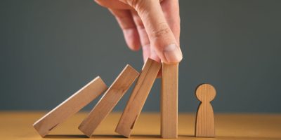 Man holding insurance with wooden people.